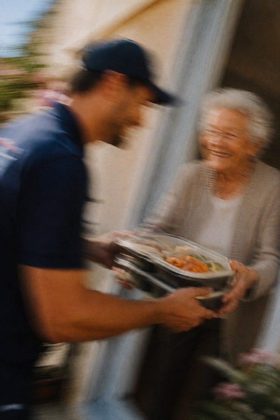 Un livreur remet un repas à une bénéficiaire